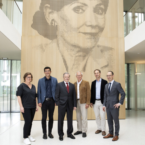 Group picture with portrait of the founder in the background.