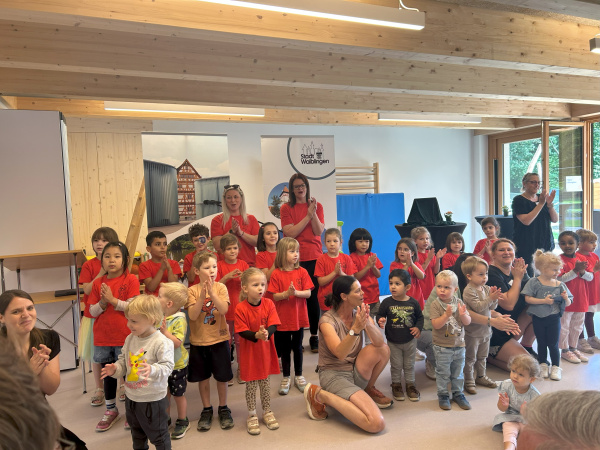 Eine große Gruppe Kinder trägt ein Eröffnungslied vor.