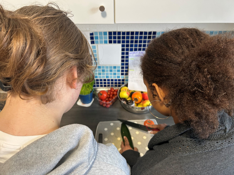 Zwei Mädchen schneiden Gemüse in der alten Küche.