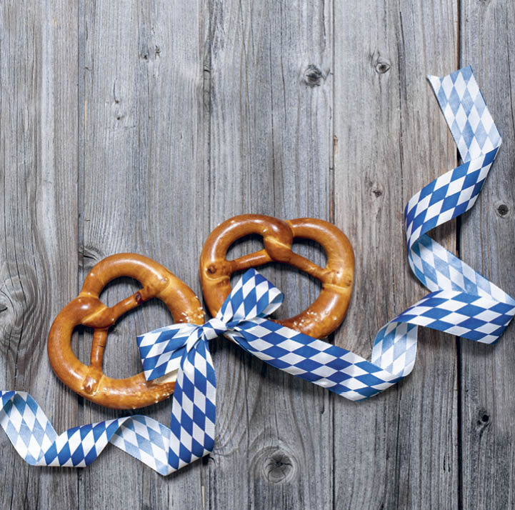 Bavarian pretzels with ribbon on wooden board as a background for Oktoberfest